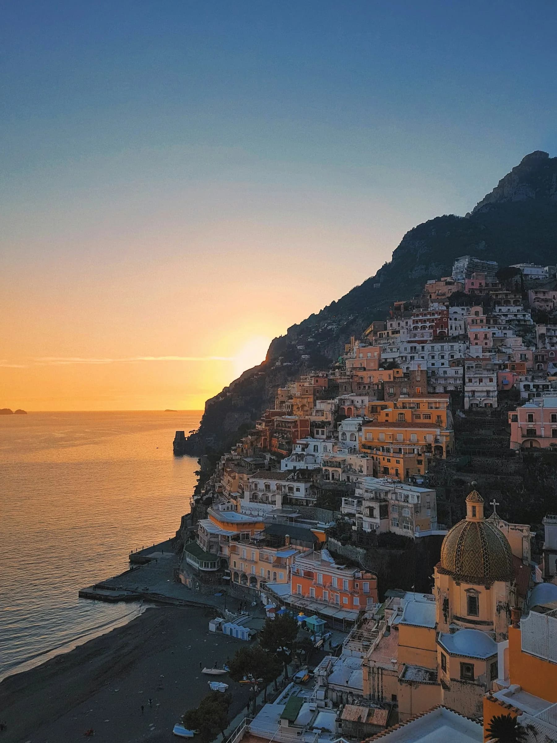 The sun going down behind Positano, the dome of Santa Maria Assunta below