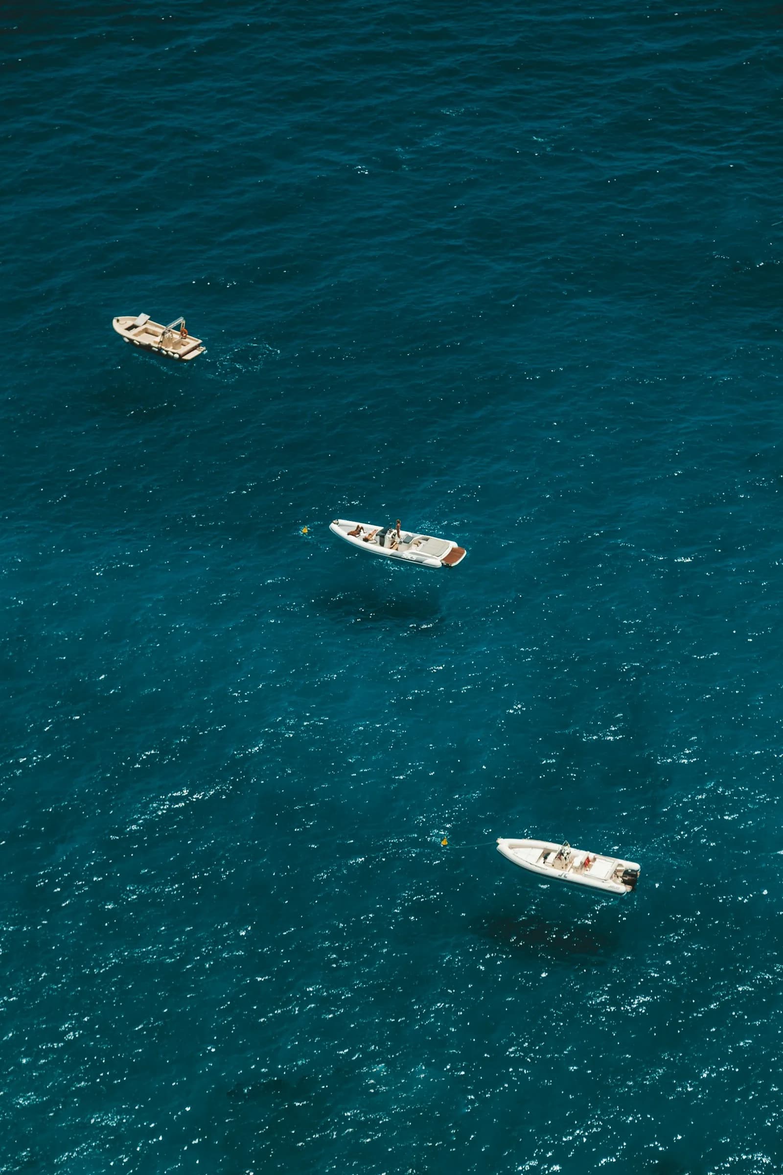 White boats on deep blue water, seen from above