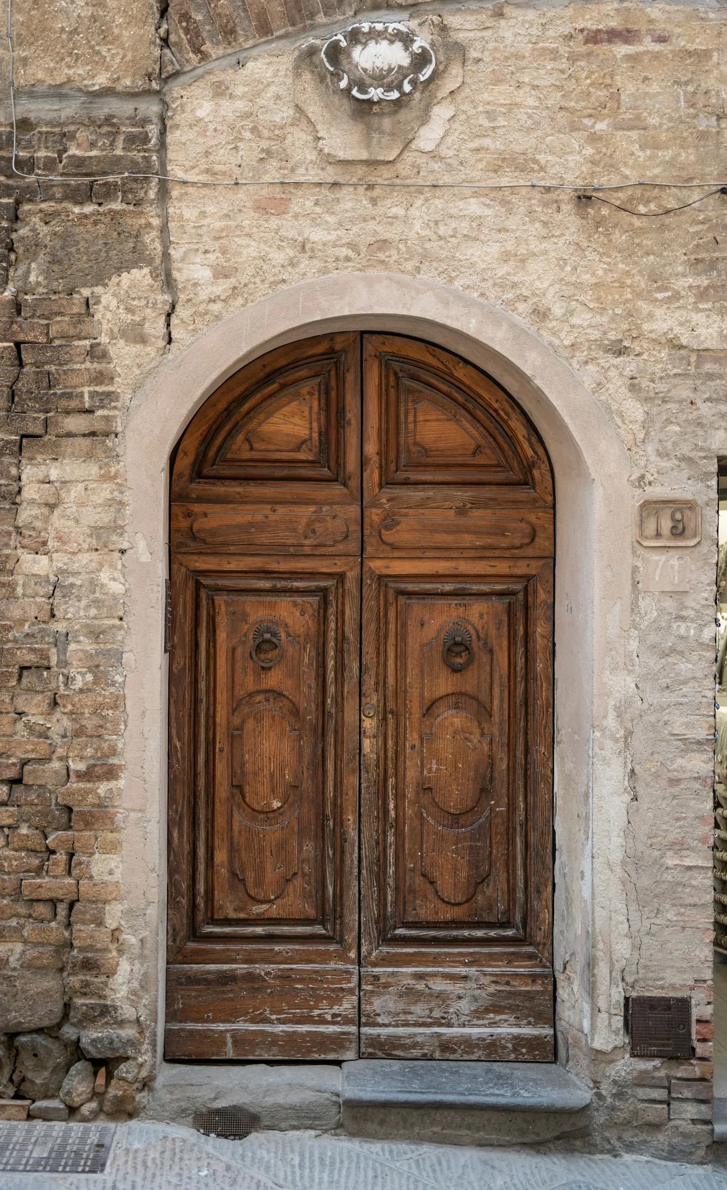 Un portone di legno ad arco in una cornice di pietra