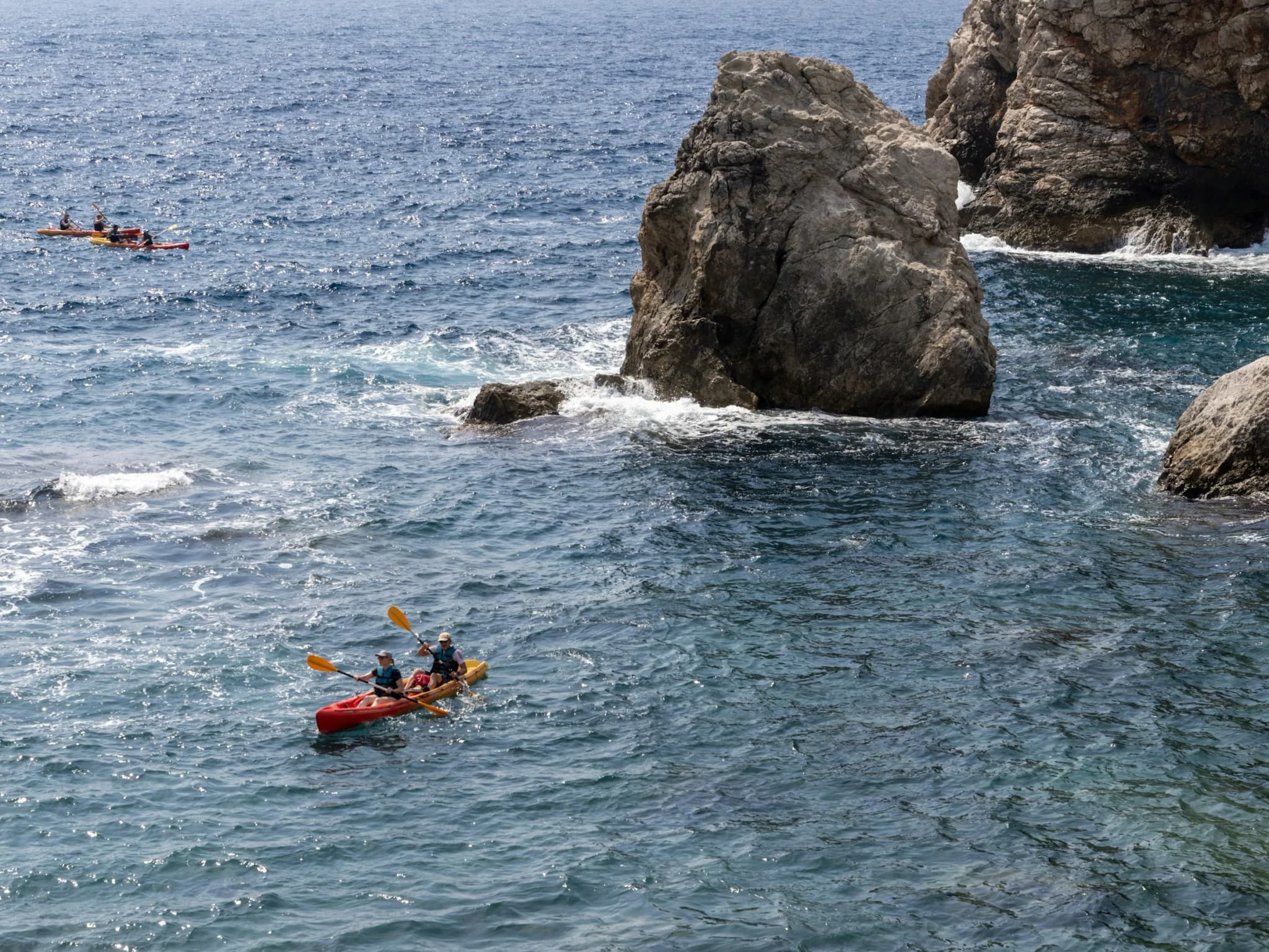 Two red kayaks among the rocks under the cliff