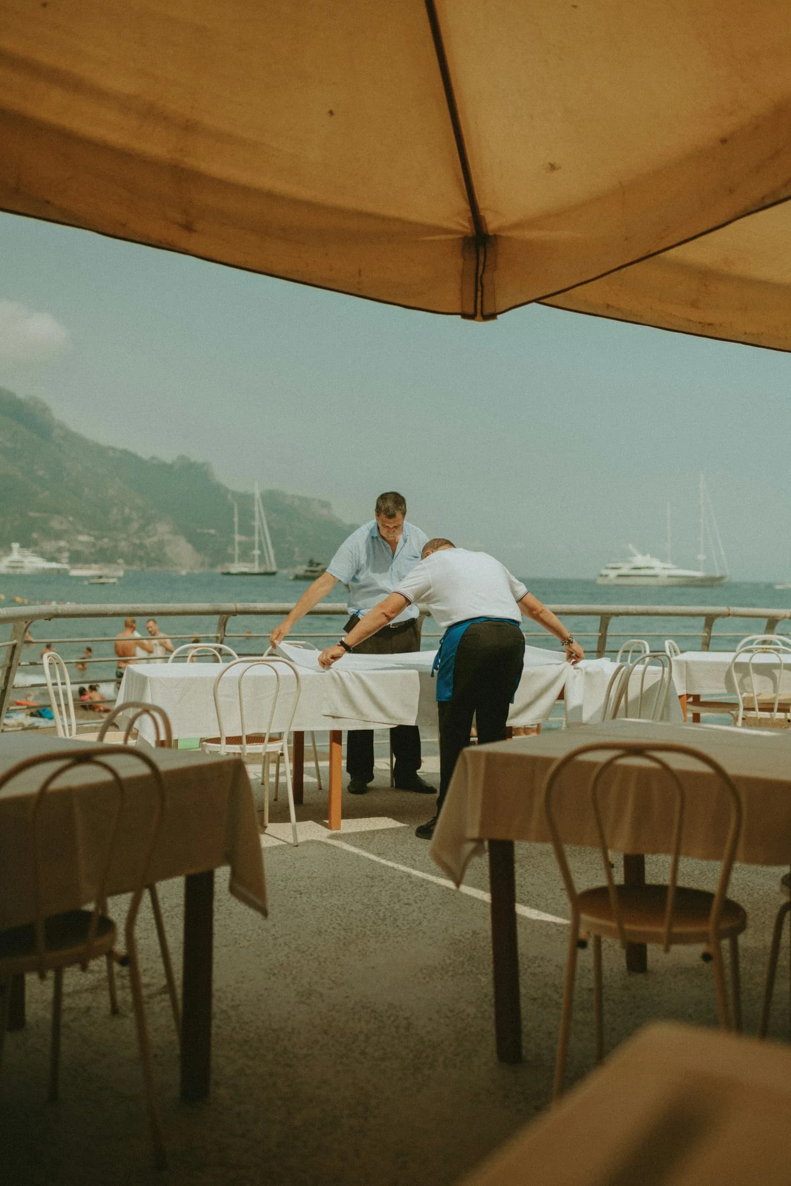 A waiter laying tables on a terrace above the sea